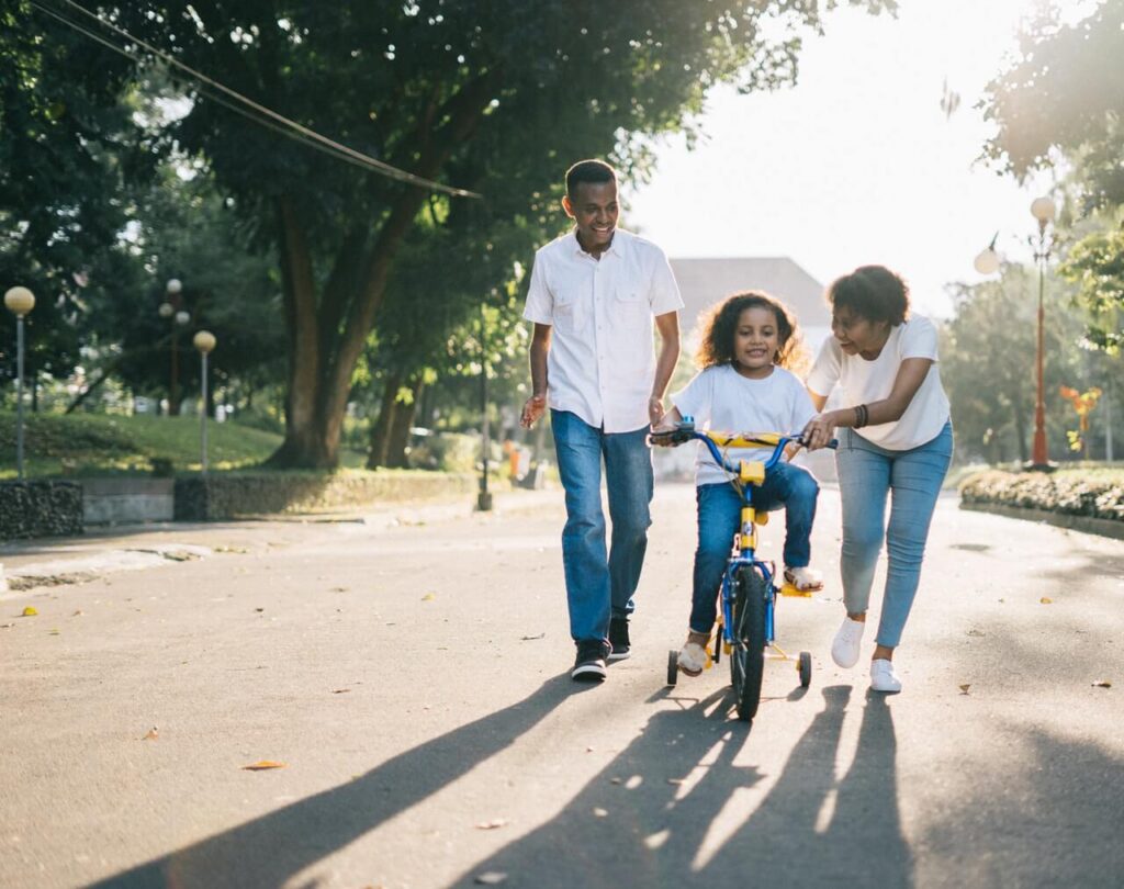 Family teaching their kid how to ride a bike
