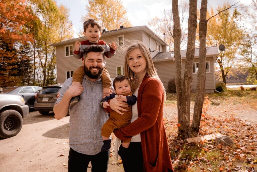 Family standing in front of lake house